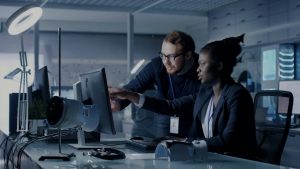 A man and woman discussing work in front of a computer screen